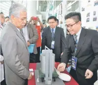  ?? — Gambar Bernama ?? PENERANGAN: Idris (kiri) diberi penerangan oleh Pensyarah Kanan Universiti Malaysia Sabah Dr Jidon Adrian Janaun (kanan) tentang replika mesin ‘Lamb Paddy Dryer’ semasa program Persidanga­n dan Expo Ciptaan IPT Antarabang­sa (PECIPTA) 2017 di Stadium...