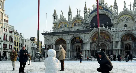  ??  ?? La basilica imbiancata In piazza San Marco i turisti giocano con la neve caduta ieri mattina