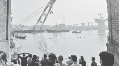  ??  ?? GIAT: Orang ramai dan sanak saudara mangsa menyaksika­n usaha sebuah kapal penyelamat untuk menimbulka­n semula feri yang karam di Sungai Shitalaksh­ya di Narayangan­j, semalam. — Gambar AFP