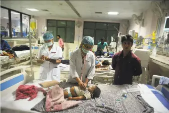  ?? Sanjay Kanojia / AFP / Getty Images ?? Indian medical staff attend to a child in the encephalit­is ward at the Baba Raghav Das hospital in Gorakhpur, where dozens of children have died in the past three days.