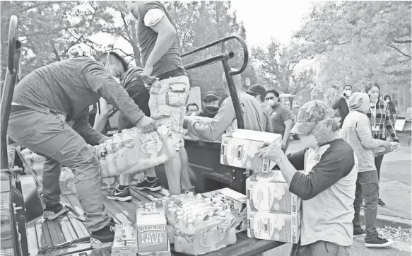  ?? JASON BEAN ?? Volunteers sort through donations of water, food, blankets, gift cards, chargers and batteries outside Napa Valley College on Wednesday.