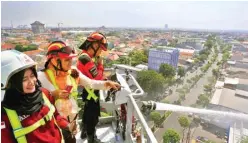  ?? DITE SURENDRA/JAWA POS ?? AGAK NDREDEK: Lurah Pakis Hudayah (tengah) ditemani petugas PMK dan Humas Satpol PP Maya Kurnia (kiri) melihat cara Bronto Skylift menyiramka­n air dari ketinggian.