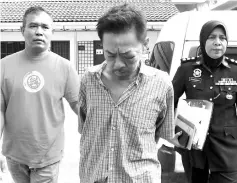  ??  ?? You Poh Khoon (centre) being escorted by a policeman into the Magistrate’s Court. Bernama photo