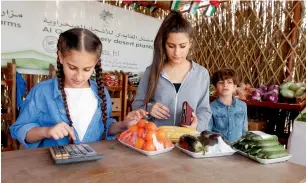  ??  ?? A family calculatin­g their bill after collecting the products. Al Qaydi says the aim of the shop is to instill honesty and trust among the people. He plans to open more self-service shops in Sharjah.