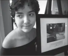  ?? CHRIS DONOVAN, THE CANADIAN PRESS ?? Cancer patient Salome Oliveira dos Santos, 16, poses with one of her photos from the photo voice project on display at the Sick Kids Hospital in Toronto on Monday.