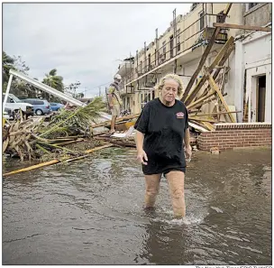  ??  ?? The New York Times/ERIC THAYERA woman (above) walks through floodwater and storm debris near a damaged apartment building Wednesday in Panama City, Fla., after Hurricane Michael slammed the Gulf Coast. At left, Kaylee O’Brien cries at not being able to find her Siamese cat after trees fell on her now-destroyed home in Panama City. Damage in Panama City was extensive, with broken and uprooted trees, and power lines down nearly everywhere.