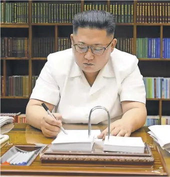  ?? AFP/ GETTY IMAGES ?? North Korean leader Kim Jong Un signs documents for the test launch of an interconti­nental ballistic missile. He is the third generation of his family to rule the isolated country.