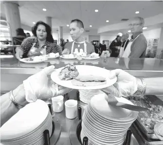  ??  ?? Volunteers serve a Thanksgivi­ng dinner to the Our Place “family.” Staff serve between 1,800 and 2,000 meals a day to Victoria’s less fortunate.