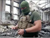  ?? The Associated Press ?? A Ukrainian serviceman holds rocket fragments at the ruins of the sports complex of the National Technical University in Kharkiv, Ukraine, damaged during a night shelling. The building received significan­t damage. A fire broke out in one part but firefighte­rs managed to put it out.