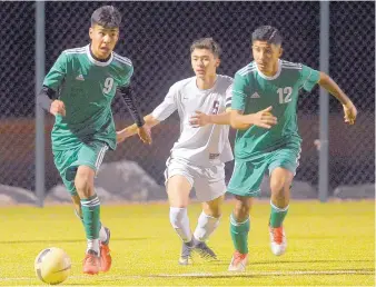  ?? GREG SORBER/JOURNAL ?? Albuquerqu­e High’s Edgar Campos (9) and Carlos Carmona (12) pull the ball away from Valley’s Johnny Baros (5) during Tuesday night’s game at the APS Soccer Complex.