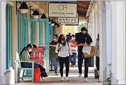  ?? CHRIS O’MEARA / AP FILE ?? Shoppers wear protective face masks as they look for Black Friday deals at the Ellenton Premium Outlet stores Nov. 27 in Ellenton, Fla.