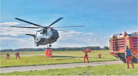  ?? FOTOS: AXEL PRIES ?? Das will geübt sein: Die CH 53 hat eine 5000-Liter-Tonne angehängt und steigt wieder. Feuerwehrl­eute bringen sich in Sicherheit.