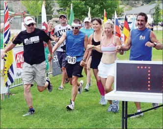  ?? Penticton Herald file photo ?? Penticton’s Dave Matheson triumphant­ly crosses the finish line at Memorial Park in Summerland with his crew at the 2013 Ultra520K triathlon.