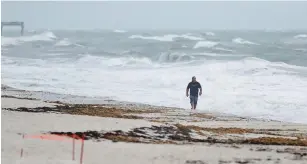  ?? WILFREDO LEE/ASSOCIATED PRESS ?? A beachgoer walks along the shore Sunday as waves churned up by Tropical Storm Isaias crash near Jaycee Beach Park in Vero Beach, Fla.