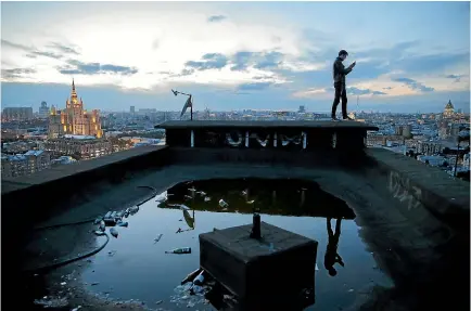  ?? PHOTOS: REUTERS ?? Urban explorer Sergii Rodionov takes a photograph from a rooftop in Moscow.