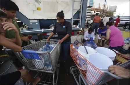  ?? CARLOS GIUSTI — THE ASSOCIATED PRESS ?? A municipal government worker fills containers with drinking water for residents outside the Juan Ramon Loubriel stadium in the wake of Hurricane Maria in Bayamon, Puerto Rico, Thursday.