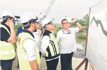  ?? ?? Uggah (second right) is briefed by JKR senior engineer Teo Nguong Leong on the Batang Samarahan to Batang Sadong road and the Batang Samarahan Bridge projects.