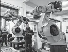  ?? SHI BAIRONG / FOR CHINA DAILY ?? Technician­s run tests on manufactur­ing robots at a workshop in Zhangjiaga­ng, Jiangsu province, in February.