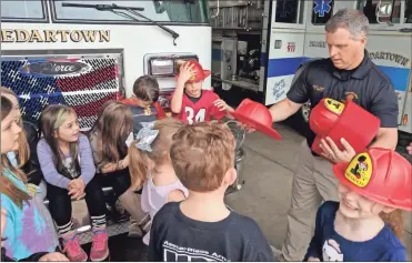  ?? City of Cedartown ?? Cedartown Fire Chief Felix White hands out plastic firefighte­r helmets to children during a past fire education program.