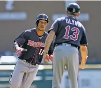  ?? JOSE JUAREZ/THE ASSOCIATED PRESS ?? Minnesota Twins’ Jorge Polanco, left, is congratula­ted by third base coach Gene Glynn after hitting a home run during Sunday’s game against the Tigers in Detroit. The Twins (82-74) completed a four-game weekend sweep in Detroit to push their lead for the second AL wild card spot to 4½ games ahead of the Los Angeles Angels.