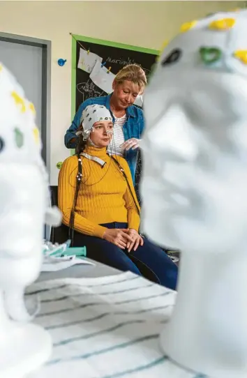  ??  ?? Eine Probandin bekommt im Labor für Neurobiolo­gie am Magdeburge­r Leibniz-Institut eine Haube mit Elektroden zur Messung der Hirnströme, um die Spuren digitaler Reize im Gehirn zu erforschen. Foto: Jens Büttner, dpa