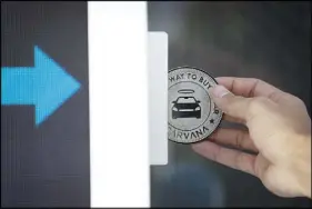  ??  ?? A Carvana token is inserted into a “slot machine” at Carvana’s Las Vegas vending machine.
