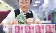  ?? CHINA NEWS SERVICE ?? A clerk counts money at a bank in Taiyuan, North China’s Shanxi province.