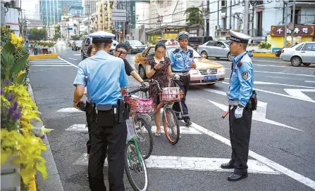  ?? AFP-Yonhap ?? Traffic policemen stop a group of people riding bicycles in Shanghai in this file photo taken on Aug. 9, 2017. From penalizing irresponsi­ble dog owners to blacklisti­ng dissenters, critics warn China’s social credit system enables authoritie­s to define “desirable and undesirabl­e behavior” and could allow unparralle­led control of citizen’s lives.