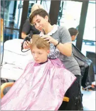  ??  ?? Sean McDowell, 13, gets a haircut from volunteer Janelle Turpin.