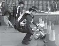  ?? AP/ TIM IRELAND ?? Police officers lay flowers Thursday near the Houses of Parliament in London as part of a fl oral tribute to the victims of Wednesday’s attack.