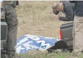  ?? BILL UHRICH/ READING EAGLE VIA AP ?? An NTSB investigat­or photograph­s a Southwest Airlines engine covering that landed in Penn Township, Pennsylvan­ia.