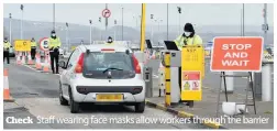  ??  ?? Check Staff wearing face masks allow workers through the barrier