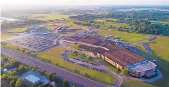  ?? MARK MULLIGAN/HOUSTON CHRONICLE ?? Cars remain in the parking lot Friday where they were left as the sun sets on Santa Fe High School in Texas, the scene of a deadly shooting earlier in the day with multiple fatalities, mostly students.