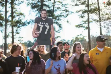  ?? Staff photo by Kayleigh Moreland ?? Janette Asher holds up a cut-out of Nick Gavriel alongside other Pleasant Grove fans on Thursday at Pleasant Grove High School. The Pleasant Grove community came together to wish the football players good luck as the team prepared to leave for...