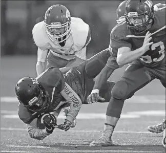  ?? SEAN D. ELLIOT/THE DAY ?? Waterford’s Christian Hightower (7) is sent sprawling by NFA’s Cameron Belton (81, obscured) and Nate Cote (24, back) in Friday’s high school football game at Waterford.