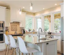  ??  ?? A broad expanse of windows in the kitchen adds an open feeling to the space, while storage is maximized around energy-efficient appliances.