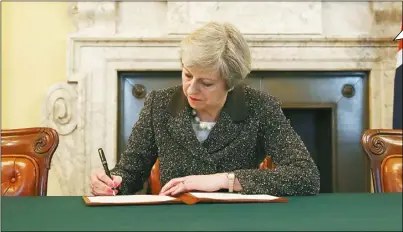  ??  ?? 英國首相梅伊在脫歐文­件上簽字，正式啟動英國脫歐。 (路透)