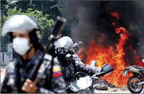  ?? AP/ARIANA CUBILLOS ?? Venezuelan national police move away from the flames after an explosion at Altamira Square during clashes with anti-government demonstrat­ors Sunday in Caracas, Venezuela.