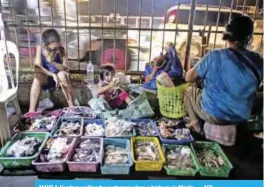 ??  ?? MANILA: Vendors waiting for customers along a highway in Manila. — AFP