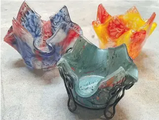  ??  ?? In full bloom: Enjoy vibrant shades of summer all year round with these fusion glass votive candle holders. Shaped like tulips, they sell for $15.95 or $19.95 with a wire stand.