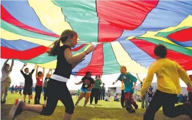  ?? AP PHOTO/AARON MARINEAU ?? Third-graders run under a rainbow-colored tarp during the annual Kansas Kids Fitness Day, in Hutchinson, Kan., in 2013.