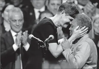  ?? [JIM YOUNG/THE ASSOCIATED PRESS] ?? Lori Lightfoot, right, and her wife, Amy Eshleman, embrace on the stage at Lightfoot’s inaugurati­on as Chicago’s mayor on Monday. Applauding in the background at left is her predecesso­r, Rahm Emanuel.