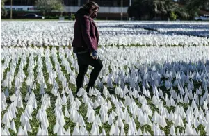  ?? (AP/J. Scott Applewhite) ?? A woman walks Monday in Washington through a field of white flags honoring the victims of the covid-19 pandemic. More photos at arkansason­line.com/113virus/.