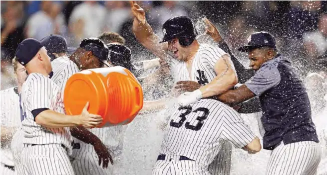  ?? Stadium.—AFP ?? NEW YORK: Matt Holliday #17 of the New York Yankees is congratula­ted by teammates after hitting the game winning 3-run home run against the Baltimore Orioles during the tenth inning at Yankee