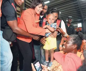  ?? IAN ALLEN/PHOTOGRAPH­ER ?? People’s National Party President Portia Simpson Miller holds a child with assistance from her close-protection officers.