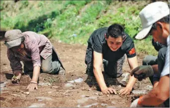  ?? NIE XIAOJI / FOR CHINA DAILY ?? A policeman stationed in Yangla, in the north of Yunnan province, helps local farmers plant seedlings.