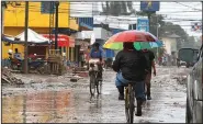  ?? (AP/Delmer Martinez) ?? People travel Monday on a street in La Lima, Honduras, ahead of Hurricane Iota’s landfall. The area is still littered with debris from Hurricane Eta.