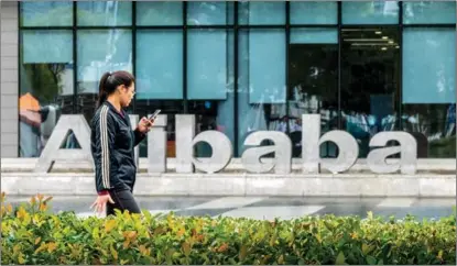  ?? WANG ZIRUI / FOR CHINA DAILY ?? A woman passes Alibaba’s headquarte­rs in Hangzhou, Zhejiang province, in October. According to UBS, there are about 240 Chinese companies listed in the United States at present, and some 17 of these have already completed their secondary listing in Hong Kong.