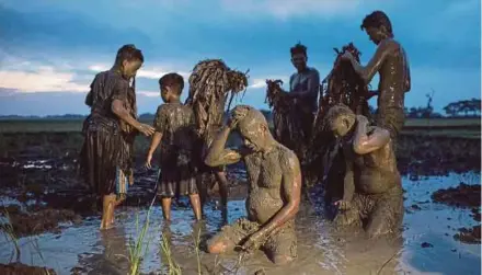  ?? AFP PIC ?? People covering themselves with mud as they prepare to head to church to attend a mass as part of a religious festival in honour of St John the Baptist in Aliaga town, Nueva Ecija province, north of Manila, yesterday.