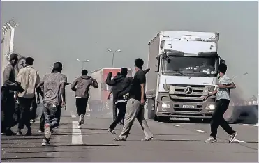  ?? Picture: AFP/GETTY ?? CRISIS: Migrants run away from tear gas during clashes with riot police in Calais